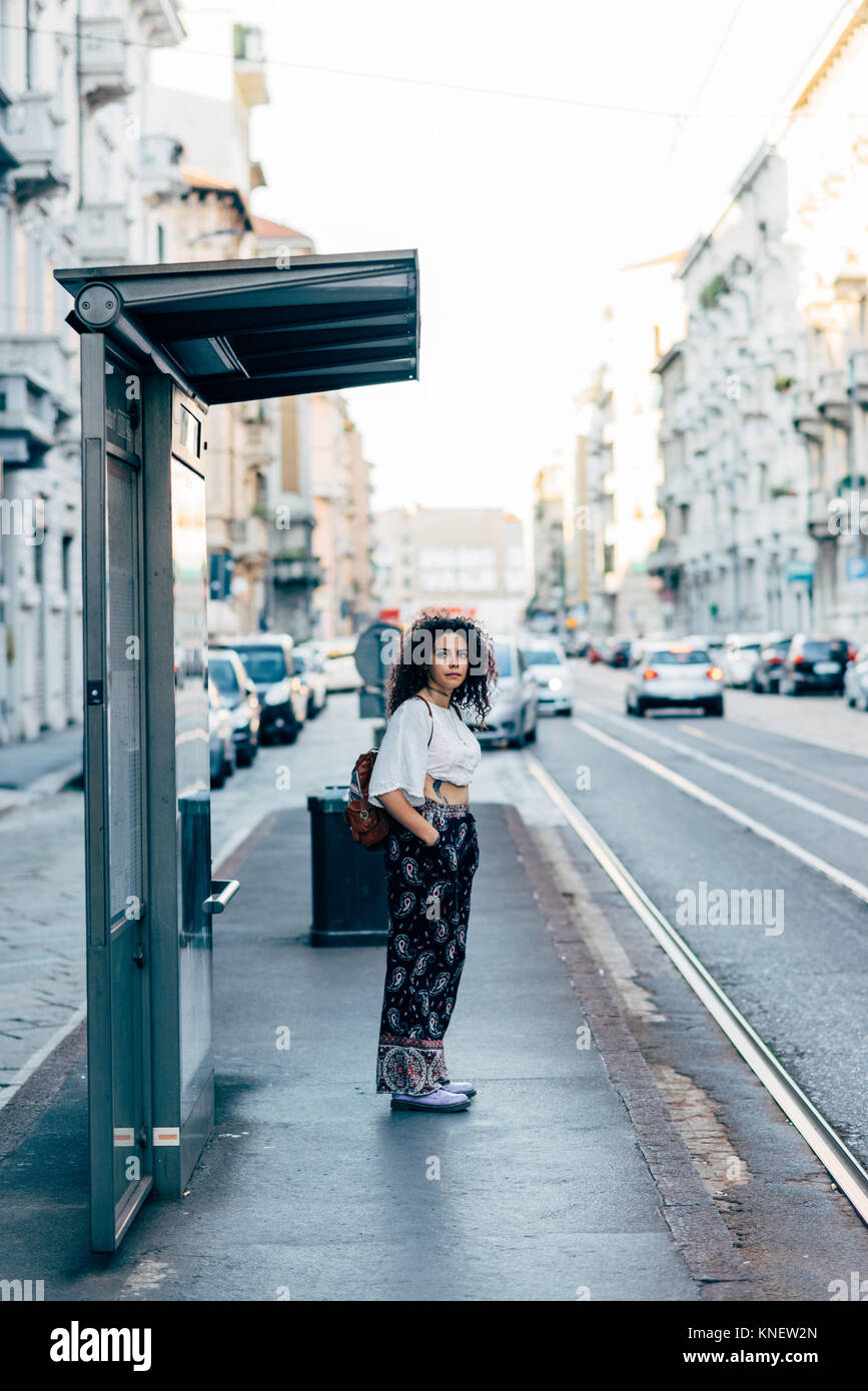 Donna in piedi presso la fermata, Milano, Italia Foto Stock