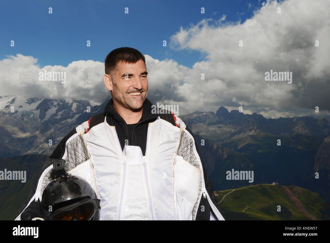 Ponticello di base indossando wingsuit guardando lontano sorridente, montagne dolomitiche, Canazei, Trentino Alto Adige, Italia, Europa Foto Stock