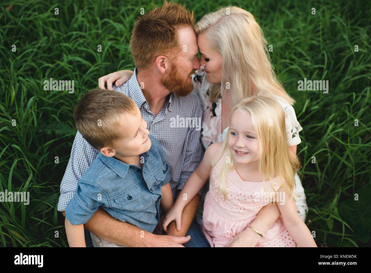 Famiglia seduti insieme sull'erba Foto Stock