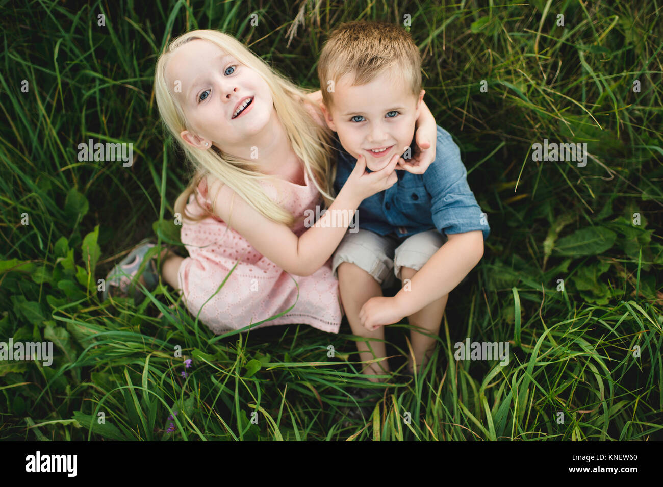 Un ragazzo e una ragazza seduta in erba alta insieme, guardando il fotocamera Foto Stock