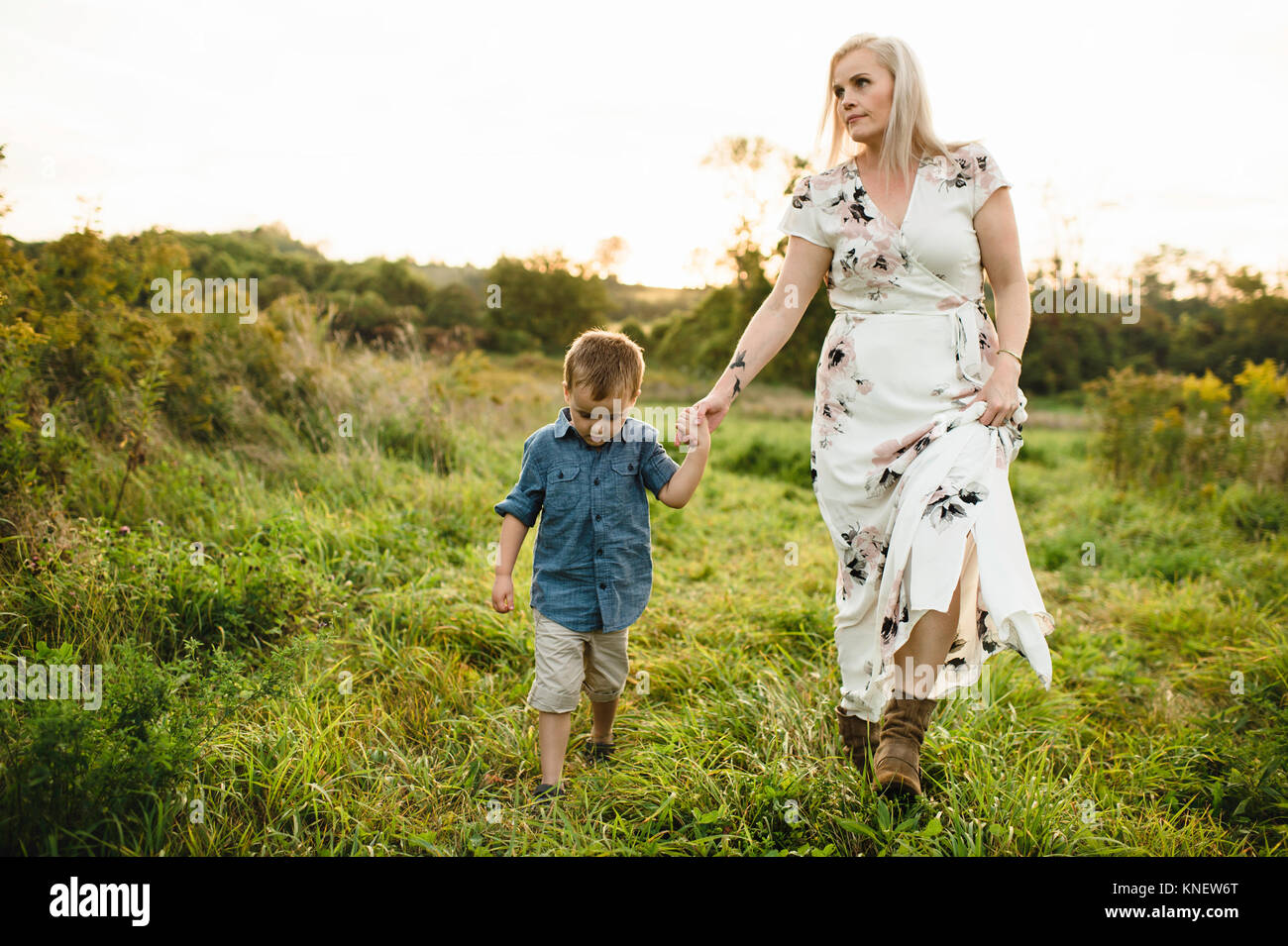 La madre e il figlio a camminare su erba tenendo le mani Foto Stock