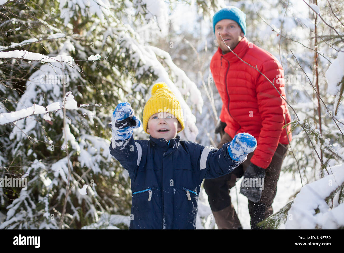 Uomo e figlio rivolta mentre si cammina attraverso la coperta di neve forest Foto Stock