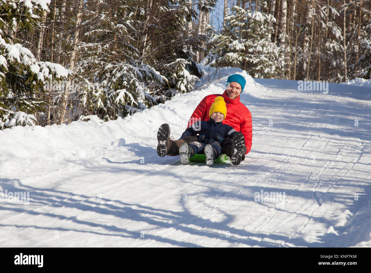 Uomo e figlio toboga in coperta di neve forest Foto Stock