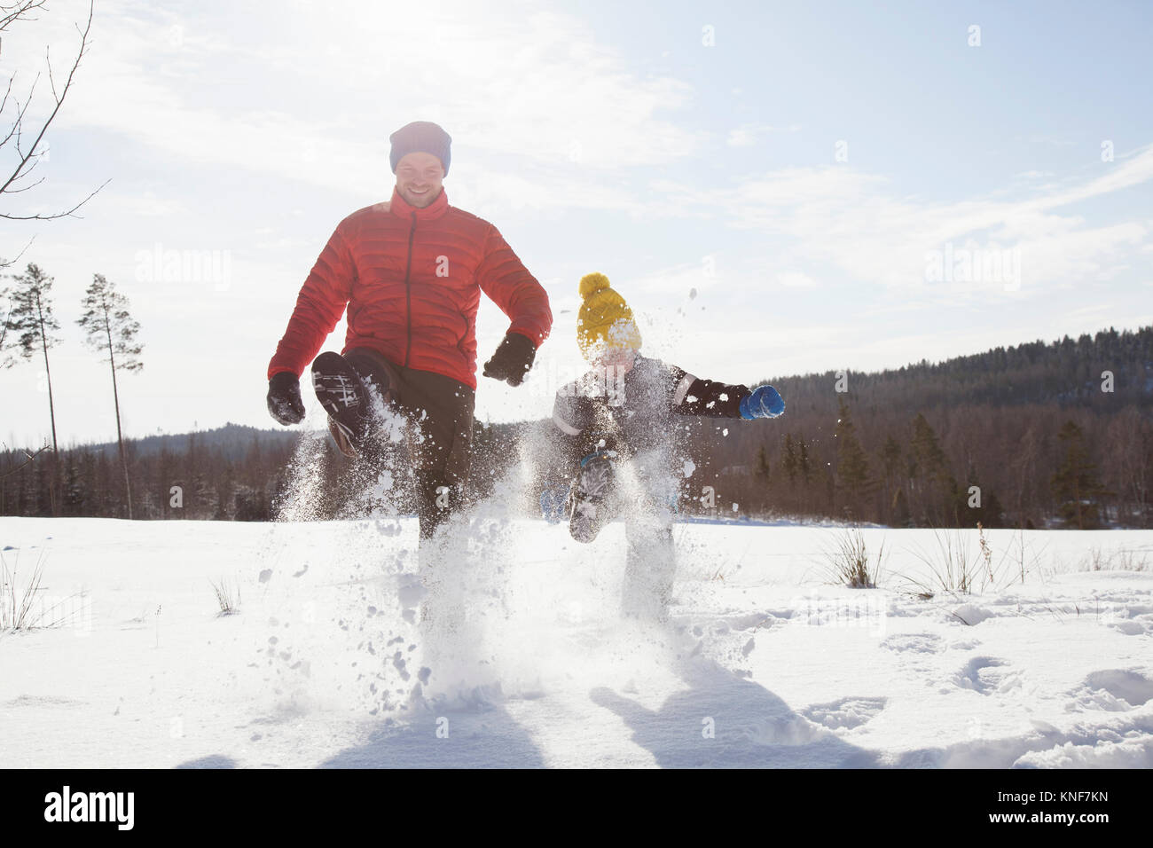 Uomo e figlio marciando in paesaggi innevati Foto Stock