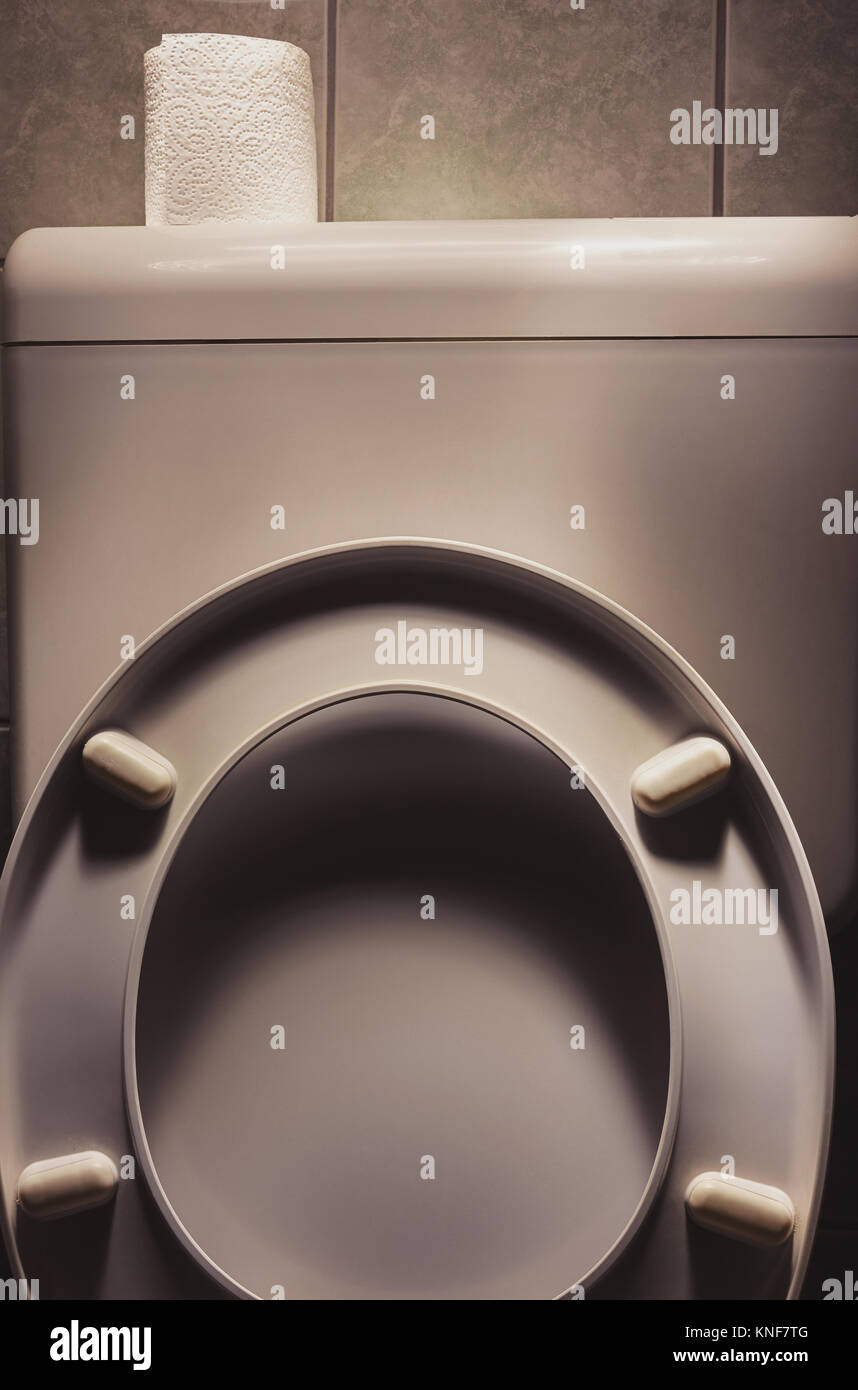 Vecchio usato wc con carta igienica in cima, accentuato di oggetti con la luce. Foto Stock