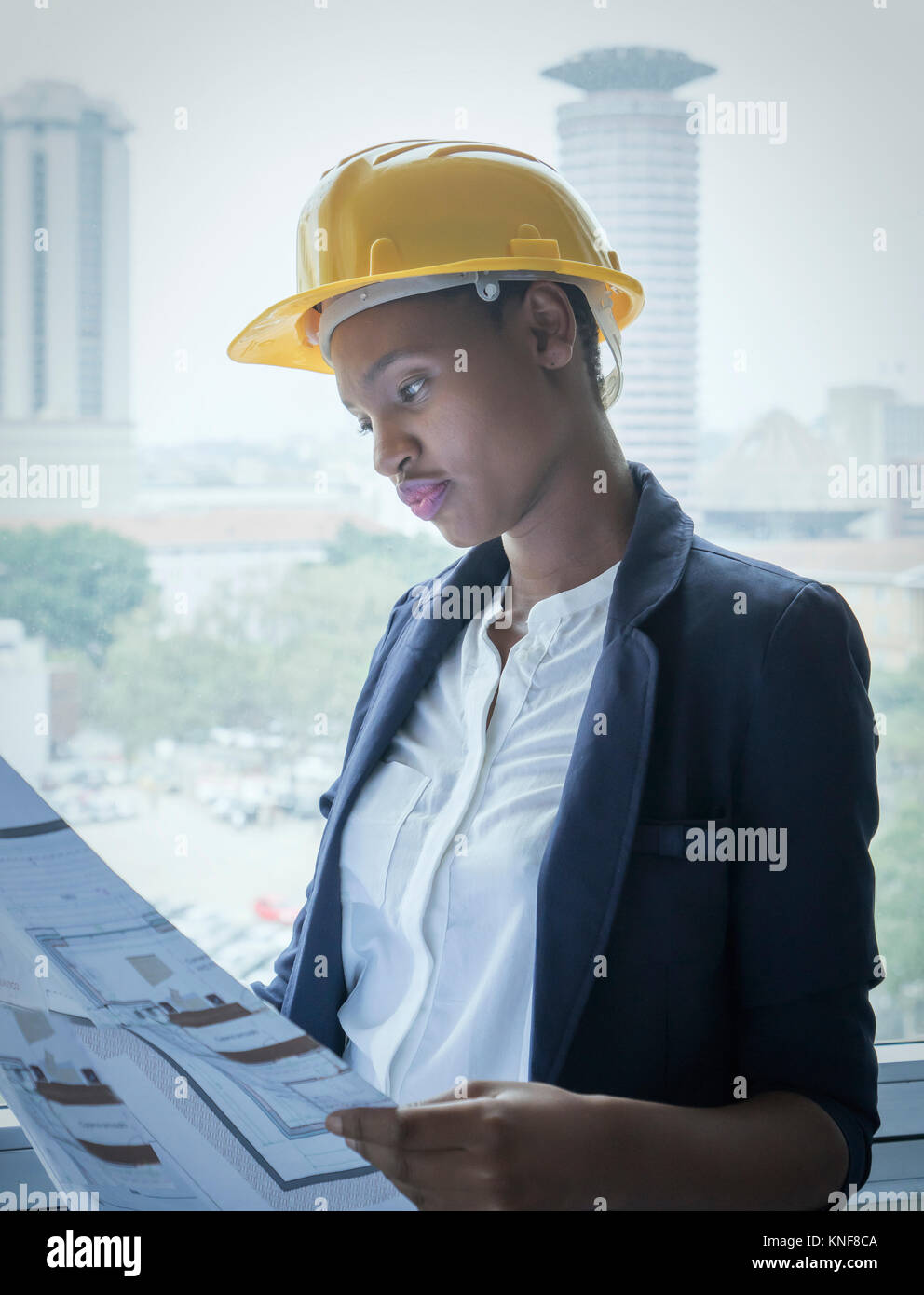 Donna in hard hat guardando i progetti di un edificio Foto Stock