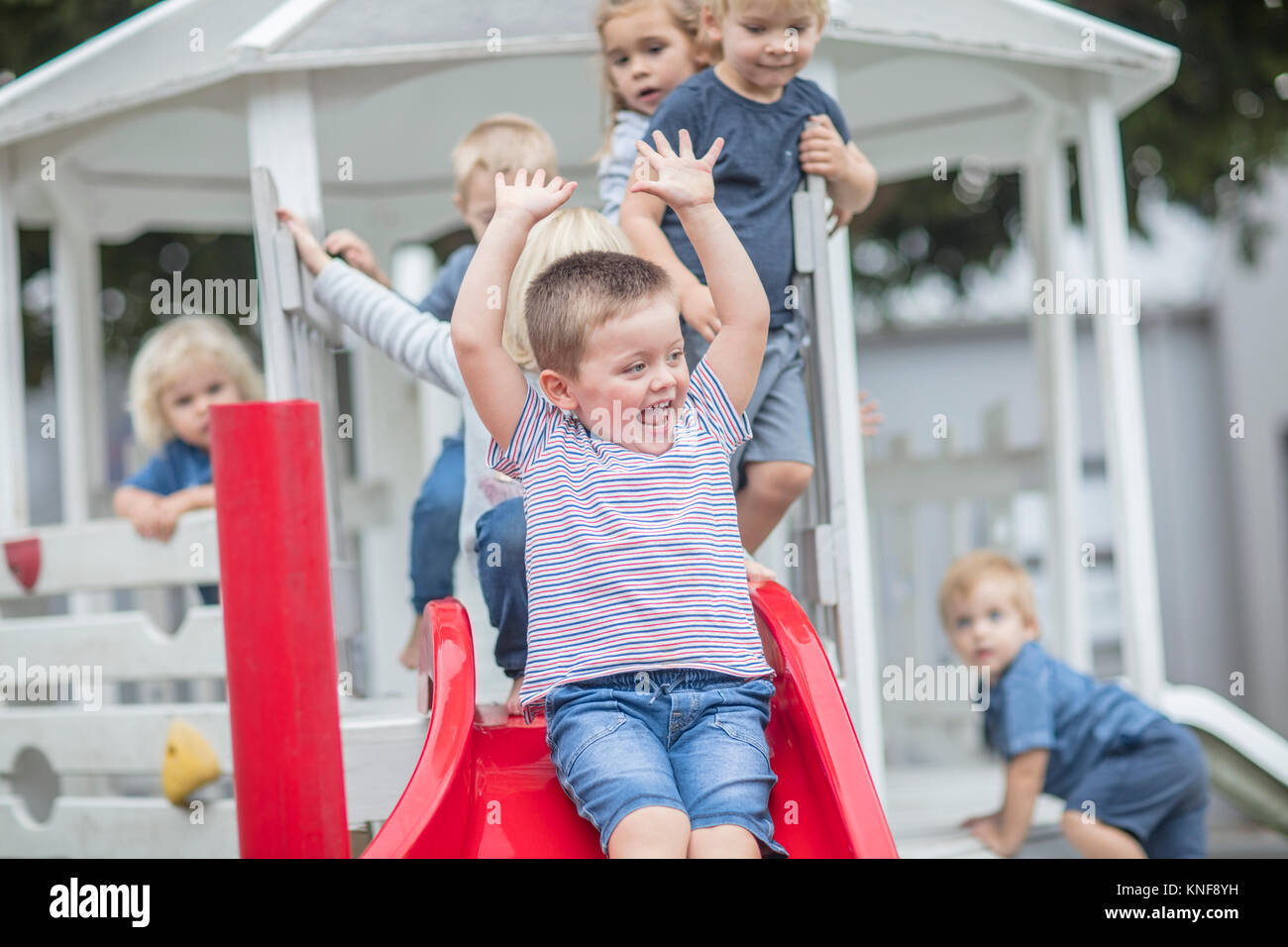 Ragazzi e ragazze in età prescolare, scorrevole sulla slitta giochi in giardino Foto Stock