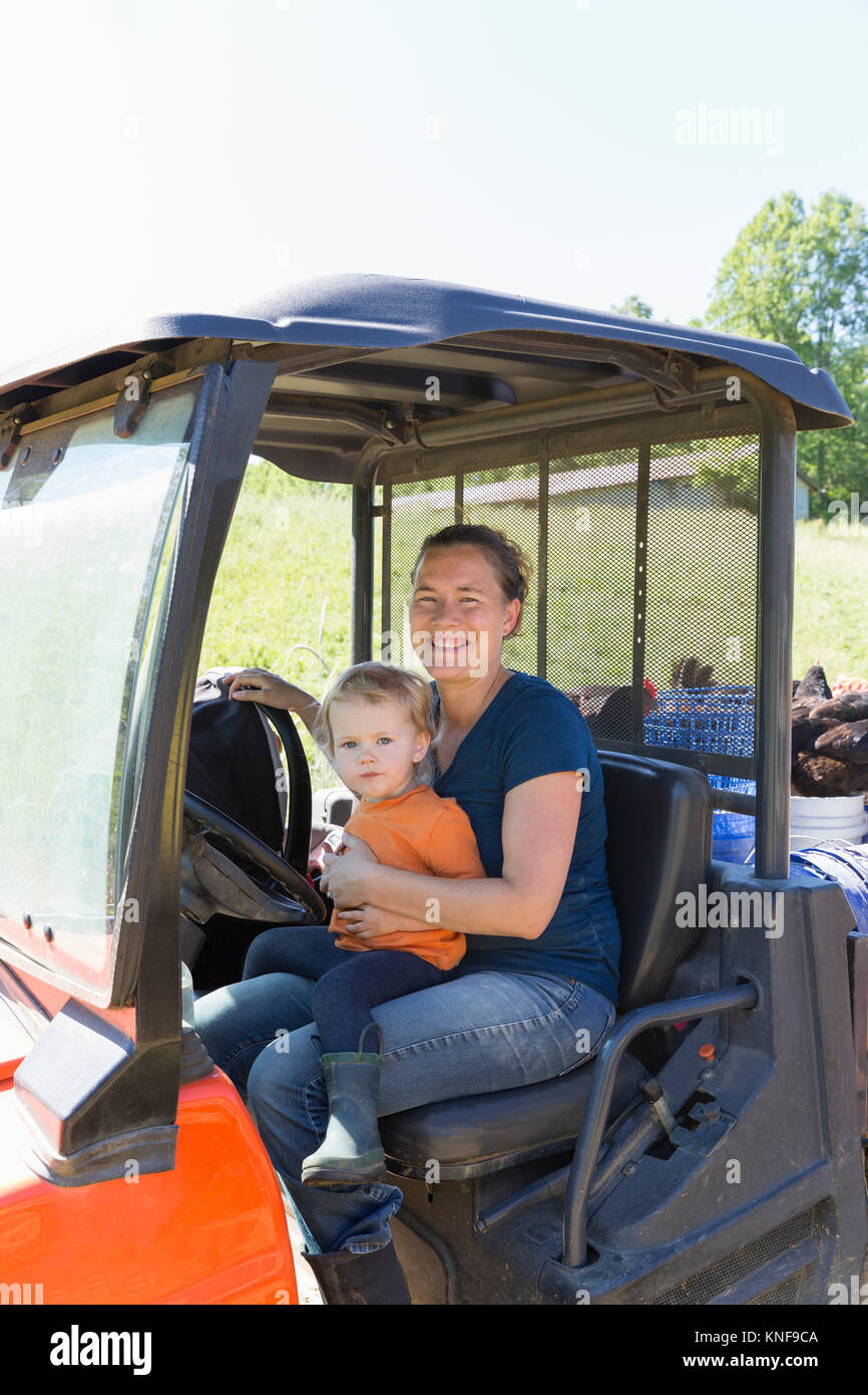 Ritratto di donna agricoltore e Bimbo bimba in carrello su free range azienda agricola biologica Foto Stock