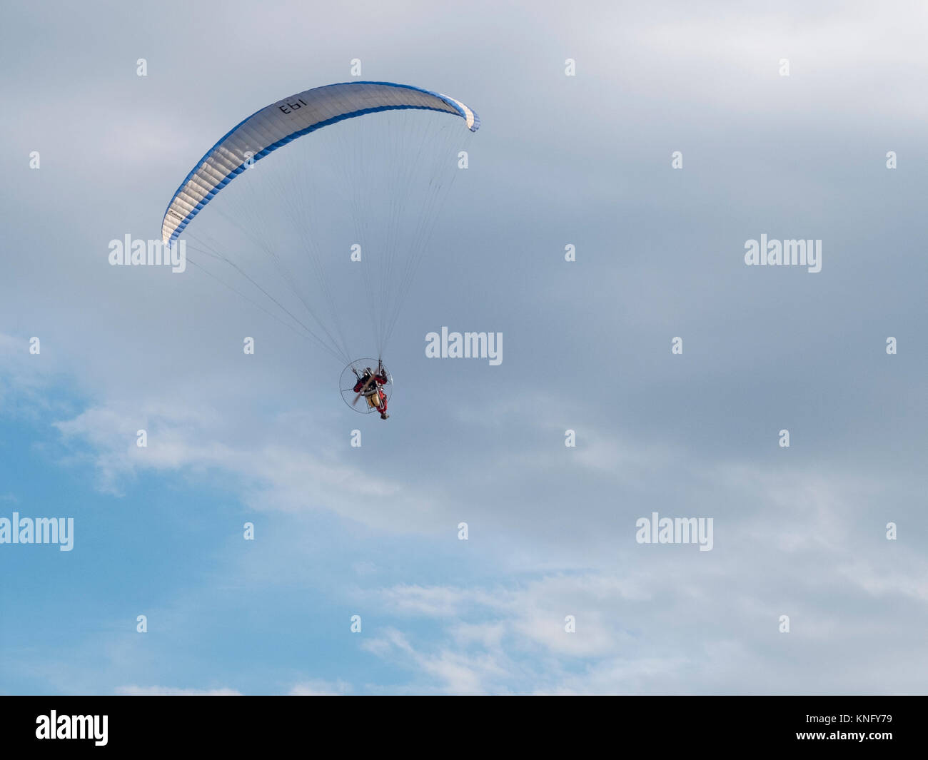 Uomo motorizzato sul deltaplano preso dal suolo sul cielo molto nuvoloso Foto Stock