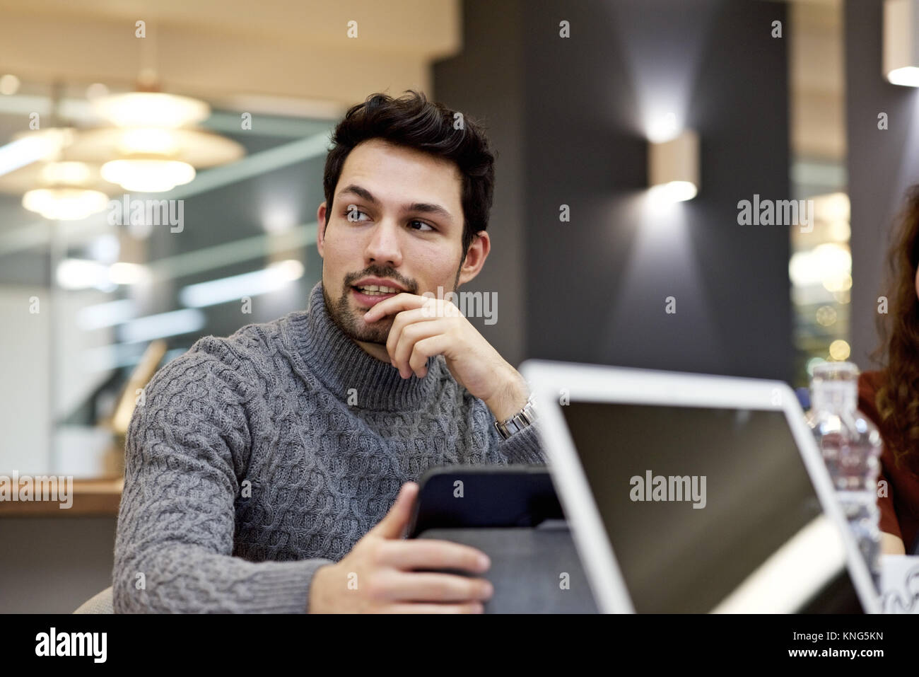 Imprenditore caucasico in abbigliamento casual reagire intelligentemente durante una conversazione con i colleghi in un incontro informale Foto Stock