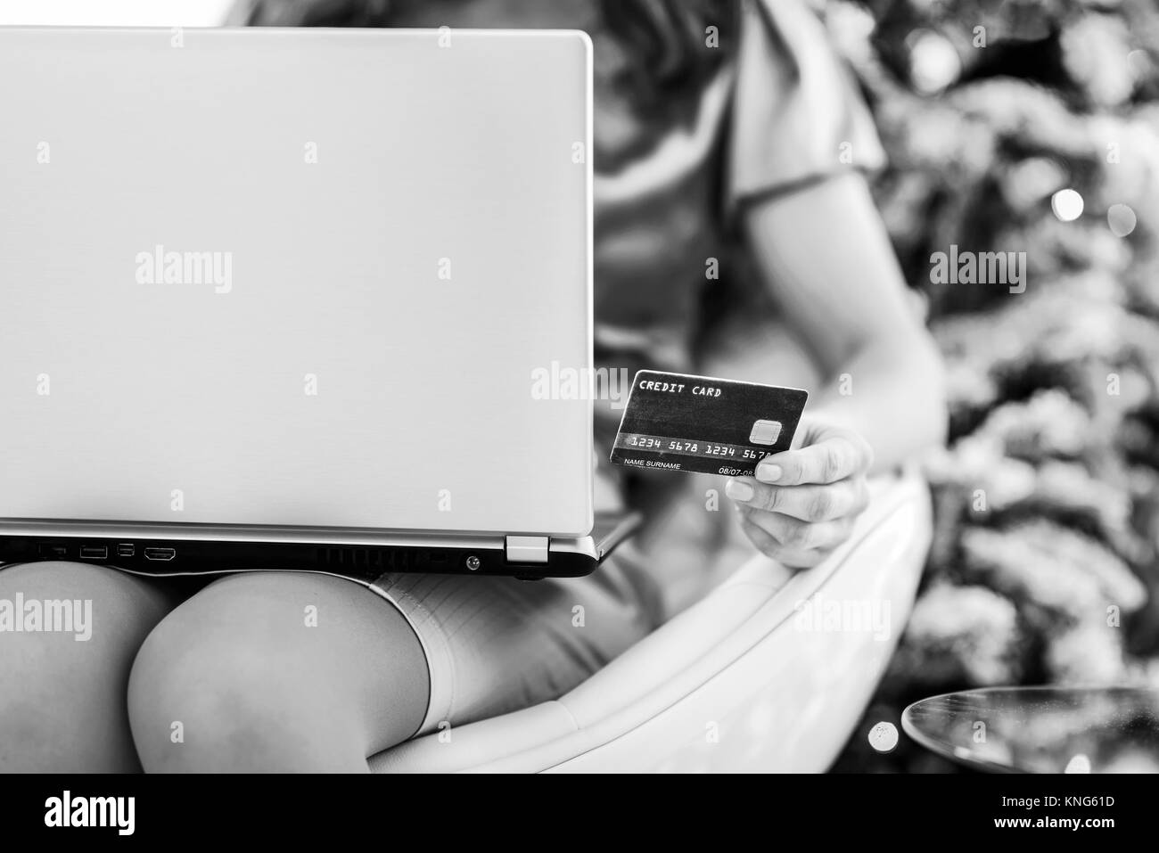 Primo piano su carta di credito in mano di donna con notebook in seduta anteriore albero di natale Foto Stock