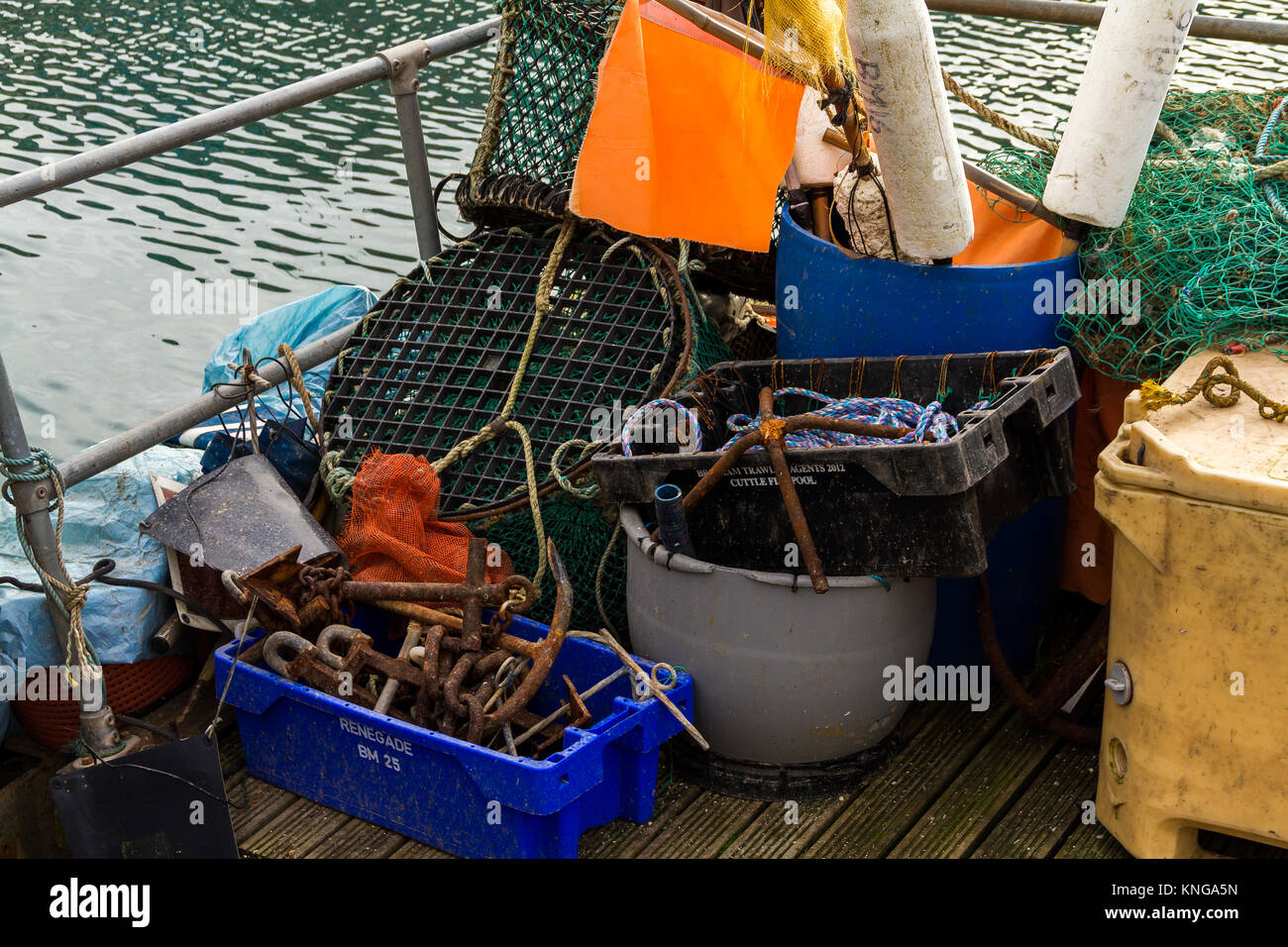 Barca generale ed industria della pesca attrezzature impilati sul lato acqua a Brixham Harbour. Brixham, Torbay, DEVON REGNO UNITO Foto Stock