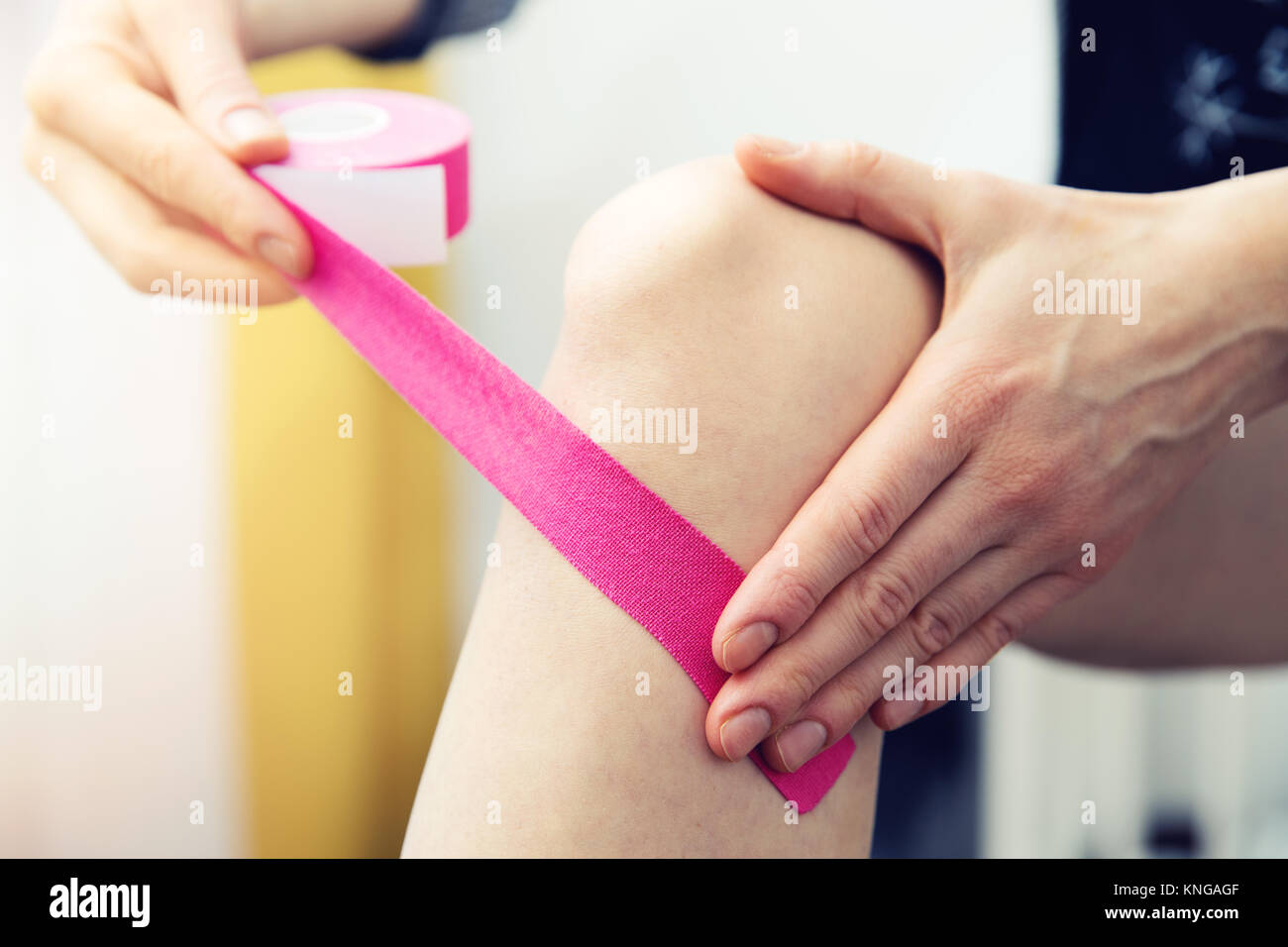 Donna con nastro adesivo il suo ginocchio con kinesio tape Foto Stock