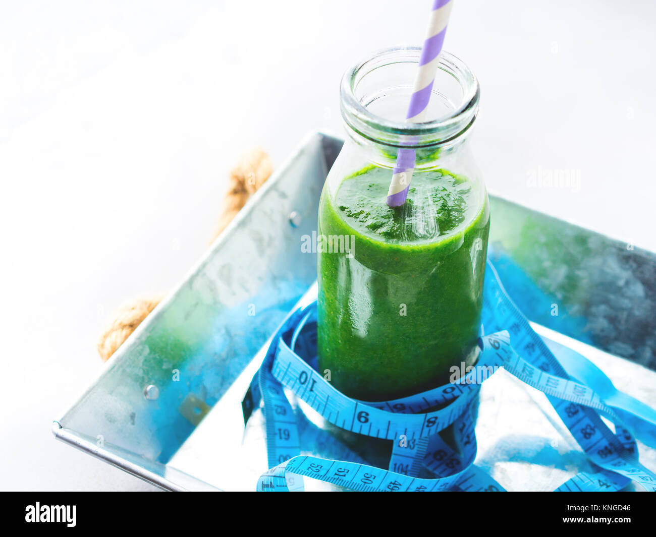 Sana dieta alimentare perdere peso concetto frullato verde colazione sul vassoio grigio blu con il metro di misura. Frutta succo vegetale una bottiglia di vetro. Foto Stock