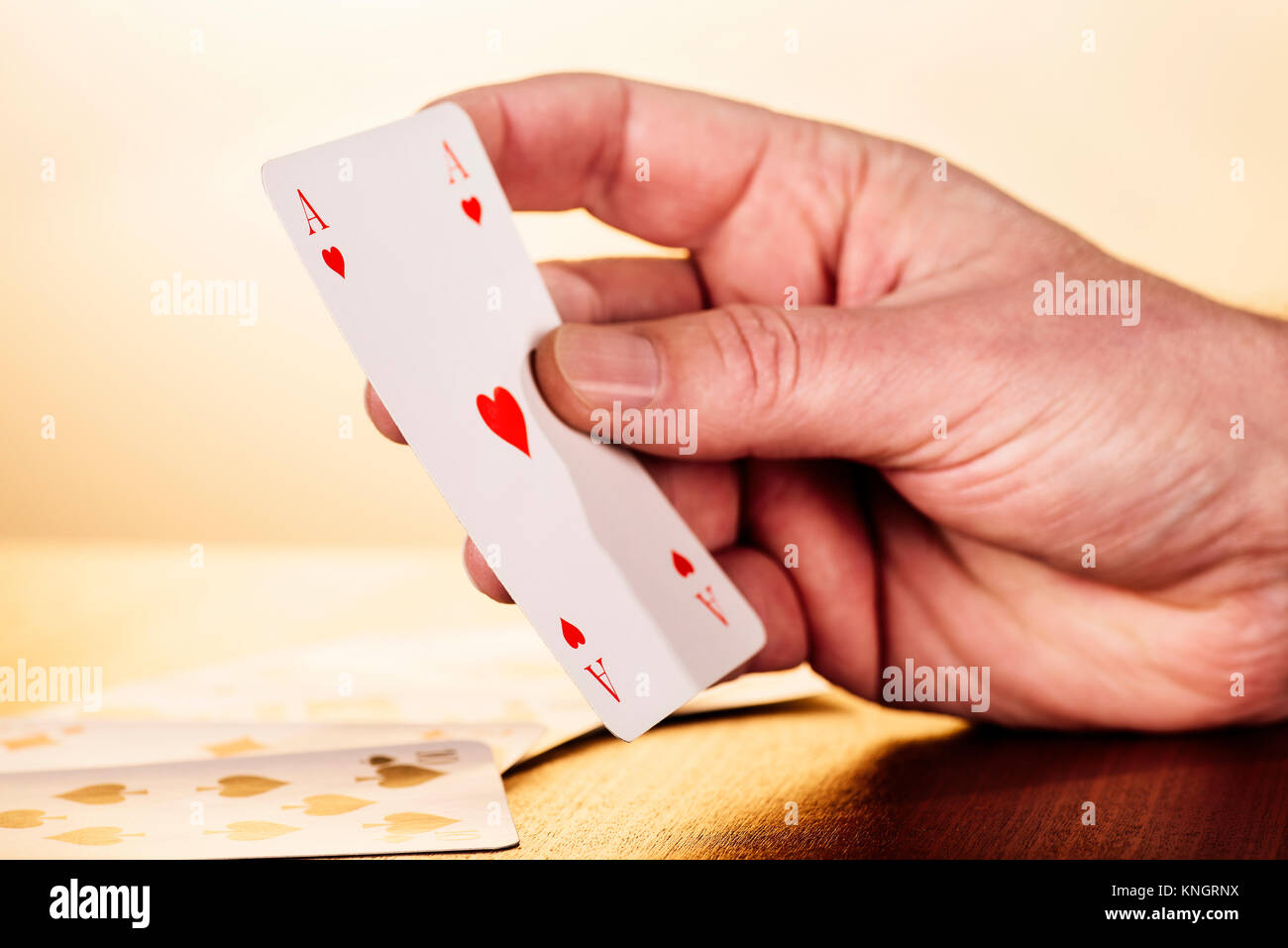 Primo piano di una mano che tiene un asso di cuori La carta da gioco. Foto Stock