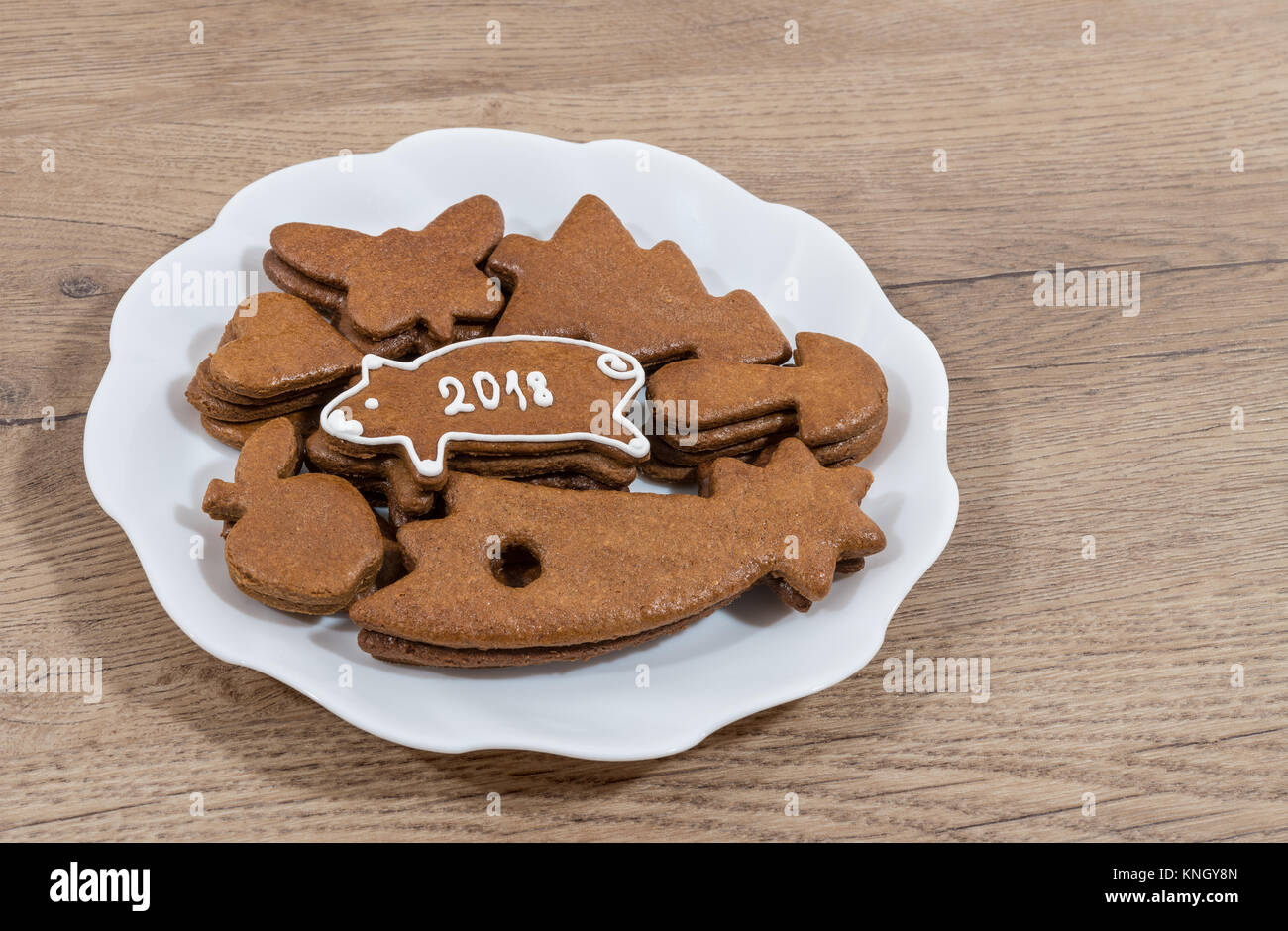Nuovo Anno di piggy per buona fortuna da Natale gingerbread. Piastra con biscotti di Natale e decorato a mano il maiale su un sfondo di legno. Foto Stock