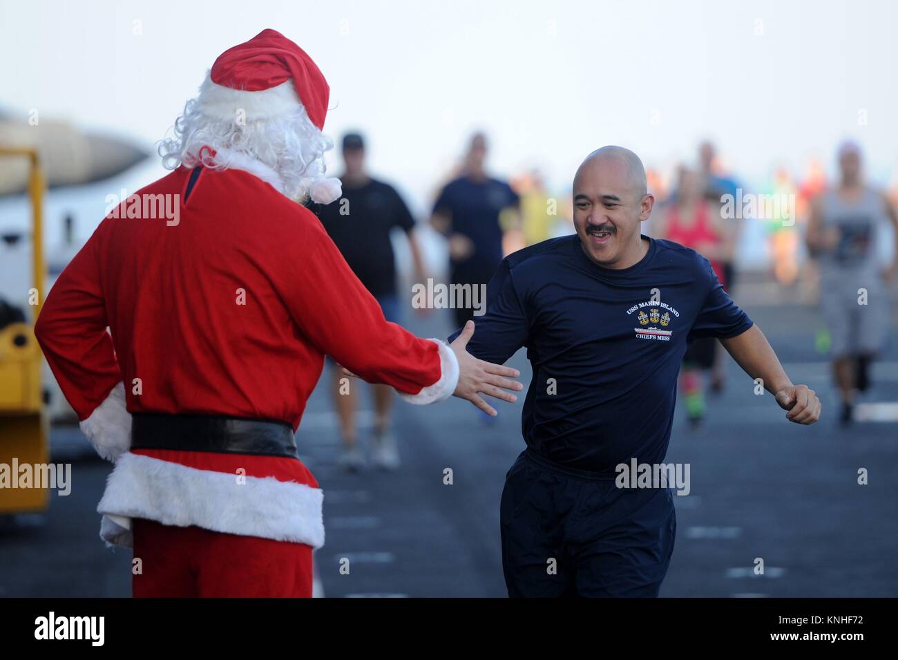 Una Santa Claus impersonator di alta cinque un marinaio NEGLI STATI UNITI durante il giorno di Natale 5K eseguire sul ponte di volo a bordo della USN Wasp-classe assalto anfibio nave USS Makin Island 25 dicembre 2016 nel Golfo di Aden. (Foto di PO1 Larry S. Carlson via Planetpix) Foto Stock