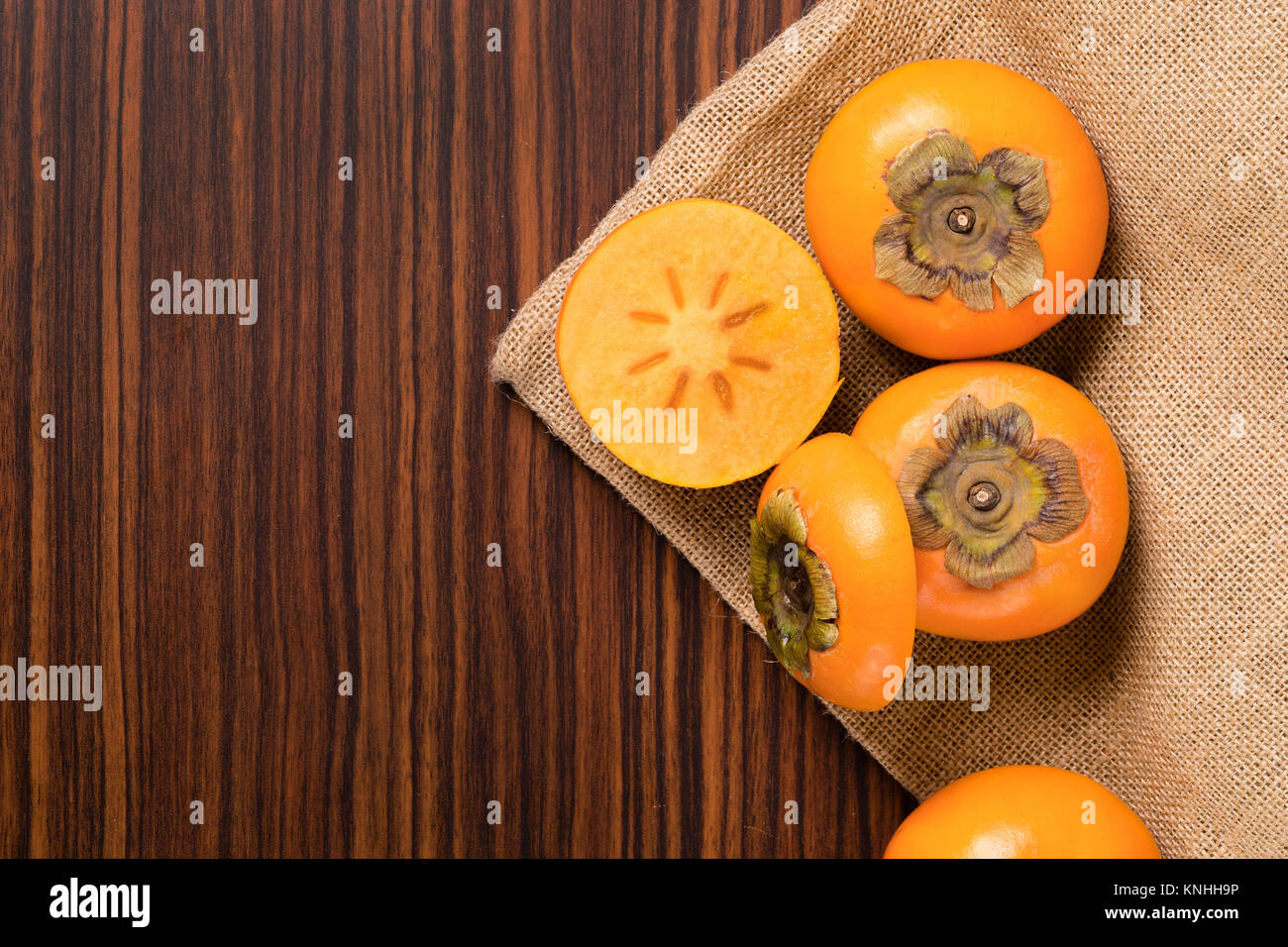 Persimmon frutta sul sacco rustico e tavolo in legno Foto Stock