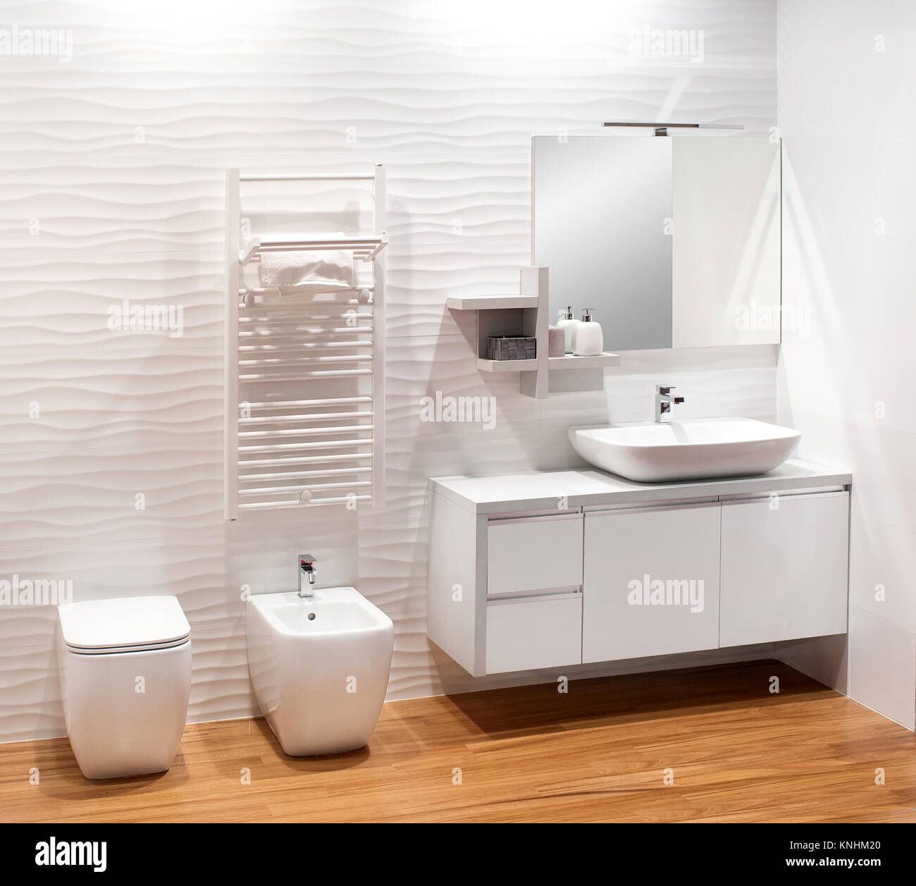 Monocromatica semplice bagno bianco con semplice mobile vanity, bidet e wc su un pavimento in legno naturale Foto Stock