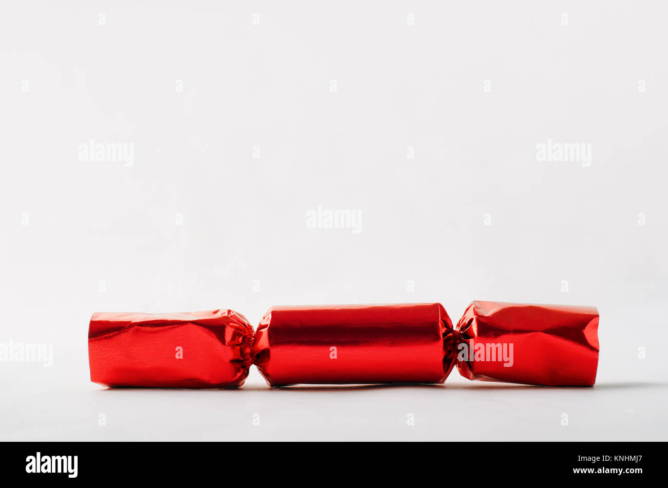 Un singolo foglio rosso Christmas Cracker sigillata con copia spazio sopra. Foto Stock