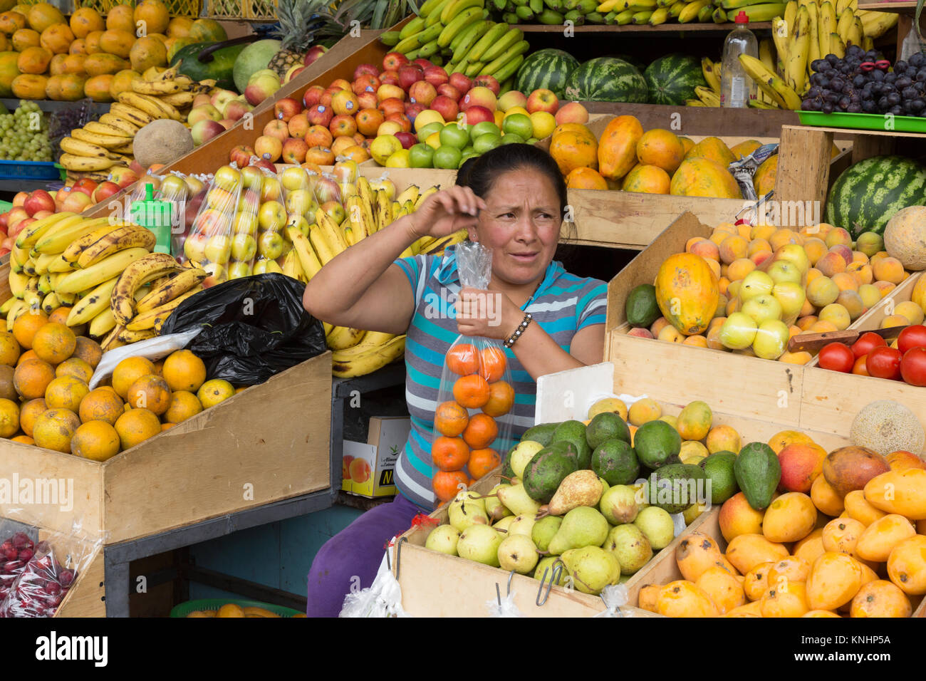 Ecuador mercato alimentare - una donna per la vendita di frutta in un mercato coperto in stallo, Gualaceo mercato, Gualaceo, sud Ecuador, Sud America Foto Stock