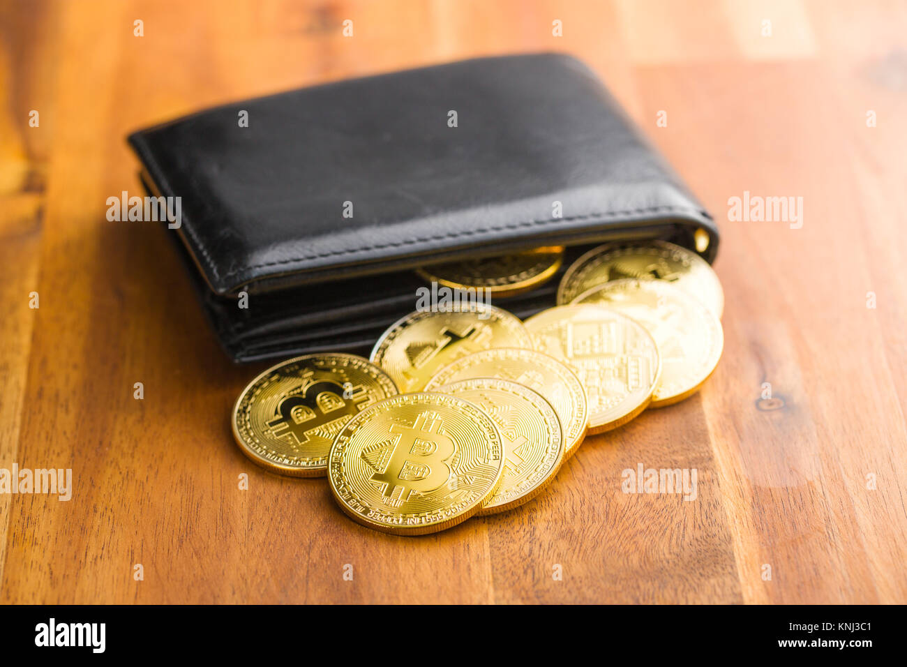 Golden bitcoins in portafoglio in pelle su un tavolo di legno. Foto Stock