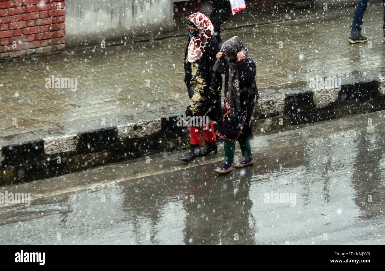 Srinagar, Indiano somministrato .KASHMIR.13.Dicembre.Una delle ragazze del Kashmir cercando coprire il suo volto come lei cammina ,durante il proseguire di neve che cade sul secondo giorno.Cinque soldati spazzato con forti nevicate in prossimità dei posti di frontiera in Kupwara e Bandipora è rimasto non rintracciabili dopo più di 24 ore il martedì. La scarsa visibilità e la caduta di neve fresca interessato il traffico aereo a Srinagar aeroporto su Mercoledì, rapporti detto. un ufficiale, hanno detto che nessun volo è operato da Srinagar aeroporto internazionale a causa di scarsa visibilità e di deboli nevicate..©Sofi Suhail/Alamy Live News Foto Stock