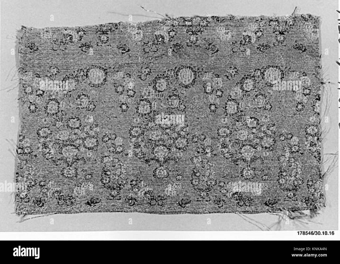 Questo frammento tessile proveniente dall'Iran, risalente al XVI-XVII secolo, è realizzato in fili avvolti in seta e metallo, con motivi broccati. Il design intricato riflette l'alta maestria artigianale dei tessuti persiani durante il periodo safavide. Foto Stock