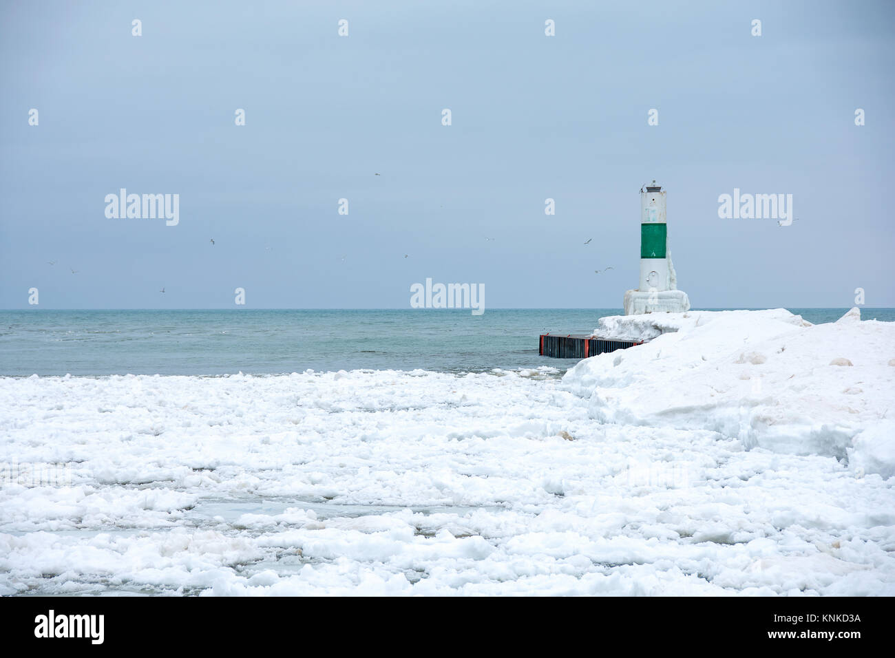 Verde e bianco faro a strisce sul Lago Michigan pier in inverno Foto Stock