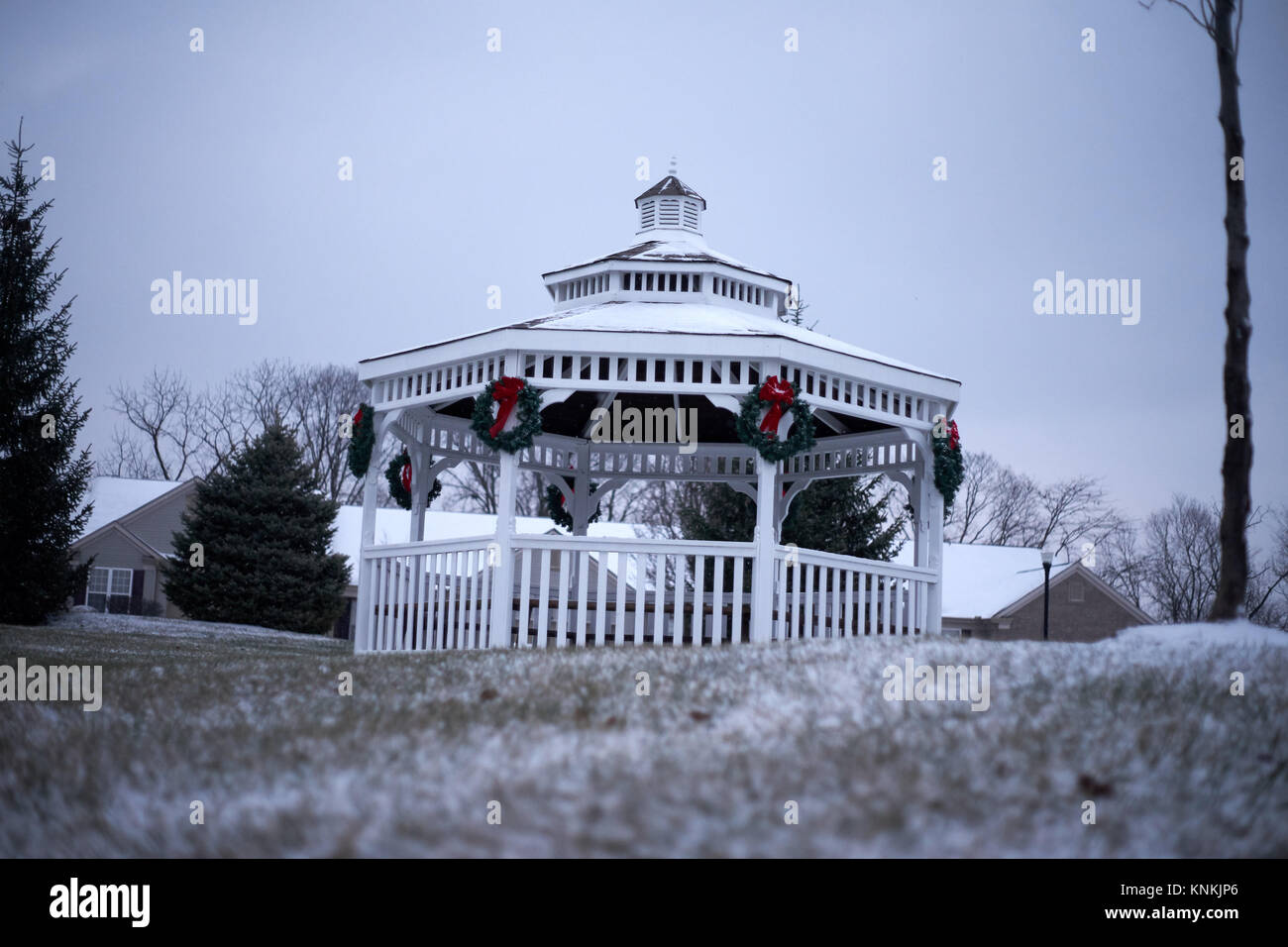 Gazebo esterno con verde di Natale ghirlande e fiocco rosso esterno con copertura di neve. Foto Stock