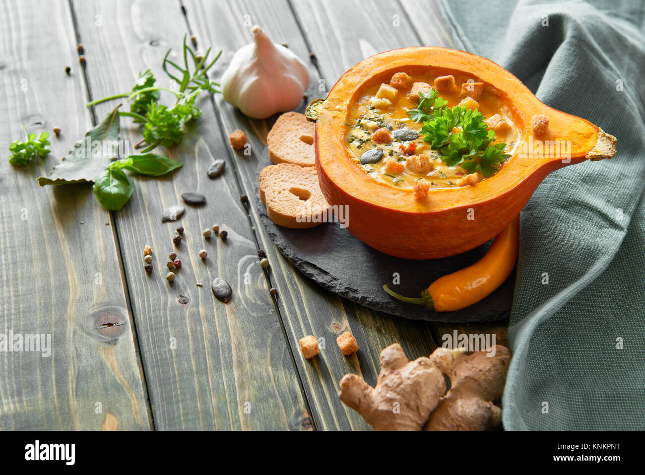 Piccante zuppa di zucca conditi con lo zenzero, peperoncino e aglio, servita in una zucca cava con crostini, prezzemolo e i semi di zucca. Autunno backgrou alimentare Foto Stock