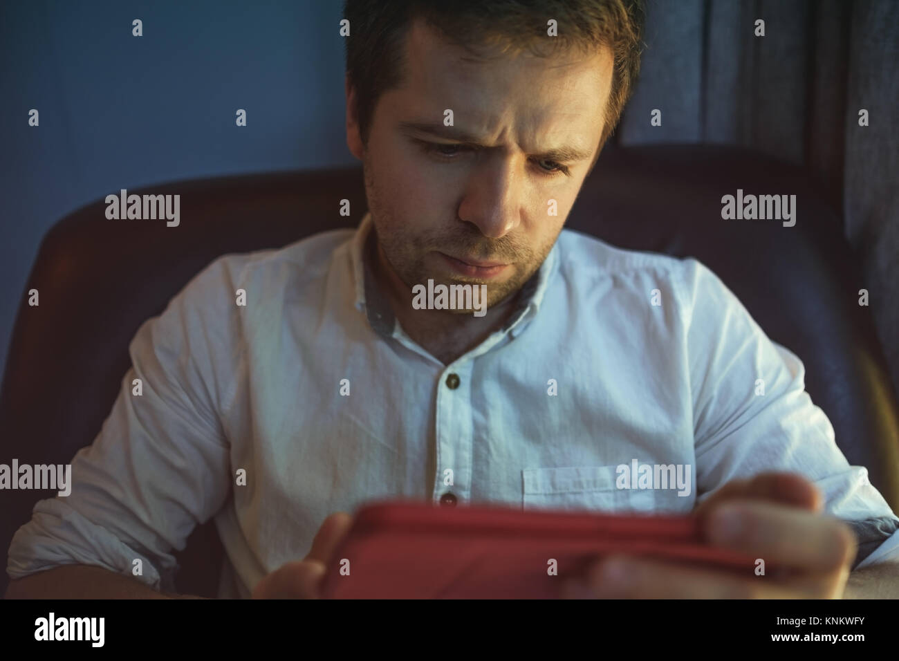 Giovane uomo caucasico al computer portatile con la riflessione della luce dalla schermata per la faccia di lavoro a casa. Foto Stock