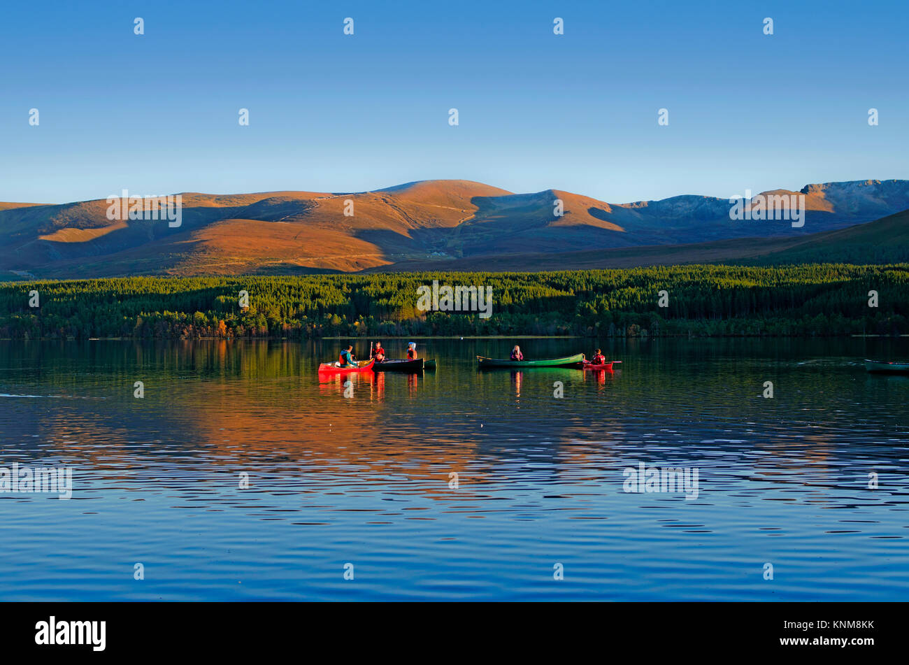 Gruppo di persone aventi le lezioni di sport acquatici sul Loch Morlich, Cairngorm altopiano sorge dietro, tranquillo pomeriggio autunnale, Highlands scozzesi, Scotland Regno Unito Foto Stock