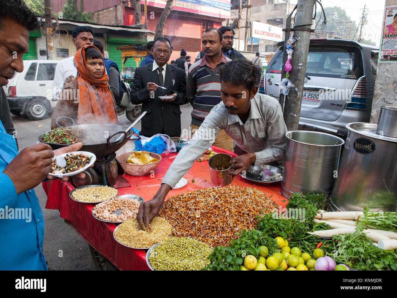 Un uomo la preparazione di un piatto di portata europea bhel puri ad una bancarella di strada nella città di Lucknow, India Foto Stock