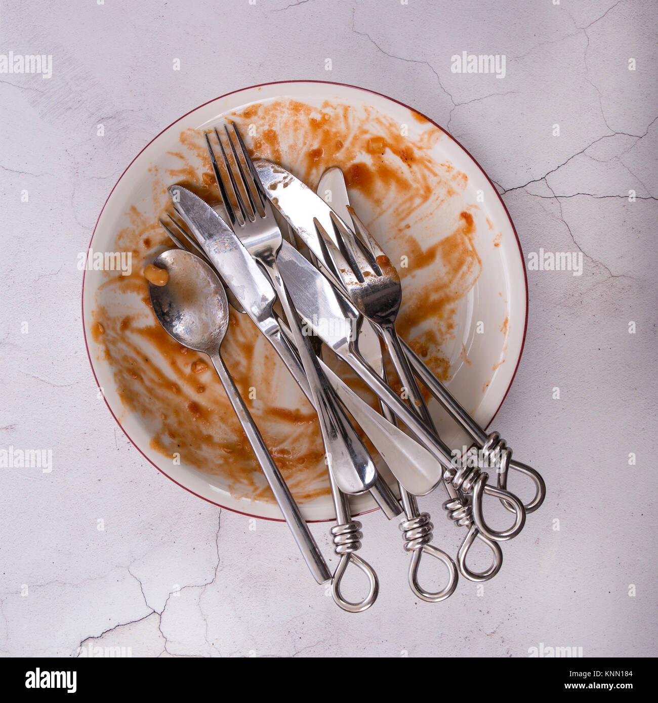 Piatto di avanzi con coltelli, forchette e cucchiaio flatlay su un sfondo marmo. Foto Stock
