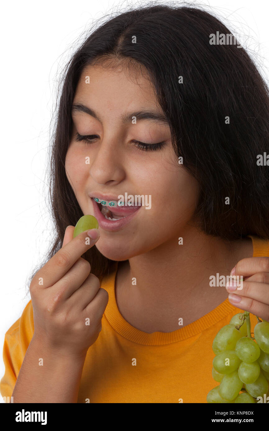 Ragazza adolescente con bretelle dentali mangiar sano verde uva Uva Foto Stock