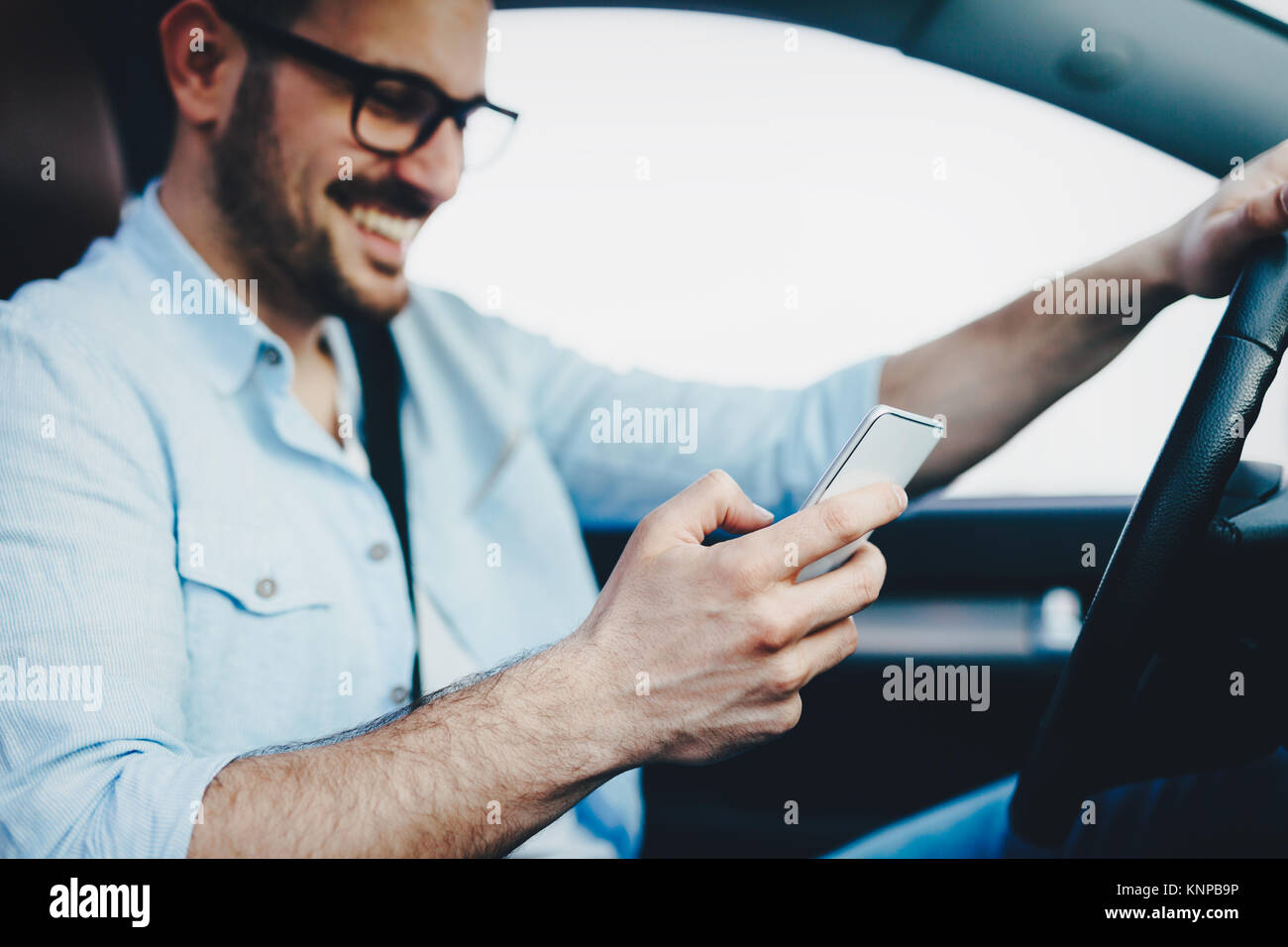 L'uomo driver utilizzando smart phone in auto moderne Foto Stock