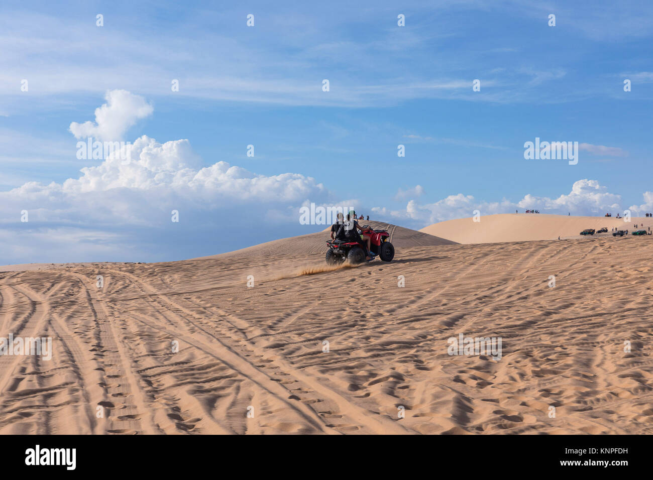 Le dune di sabbia vicino a Mui Ne. Gruppo di fuori strada sulla cima delle dune in background. Giornata soleggiata con cielo blu e nuvole. Dune di sabbia a Mui Ne , il Vietnam Foto Stock