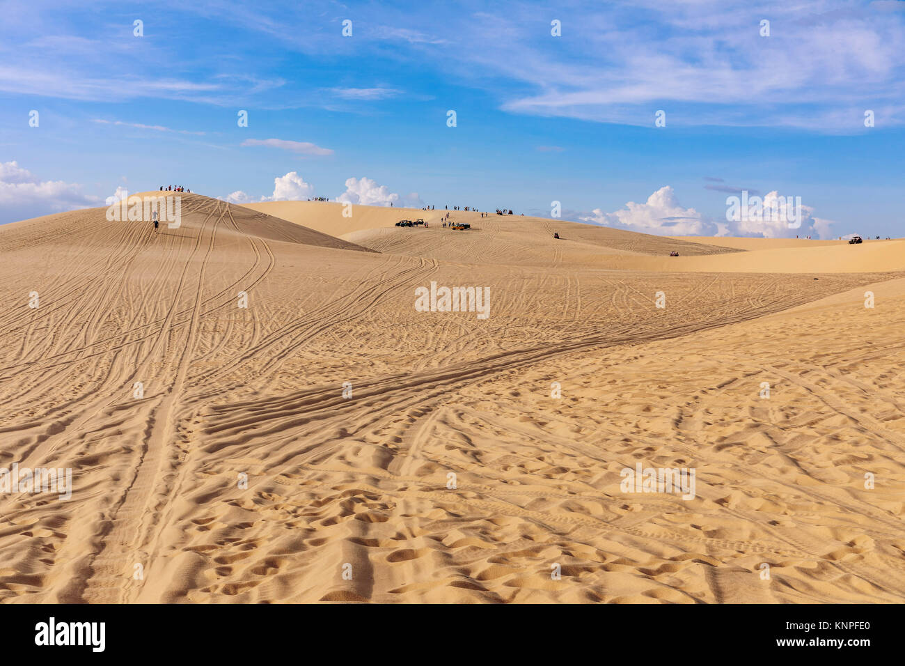 Le dune di sabbia vicino a Mui Ne. Gruppo di fuori strada sulla cima delle dune in background. Giornata soleggiata con cielo blu e nuvole. Dune di sabbia a Mui Ne , il Vietnam Foto Stock