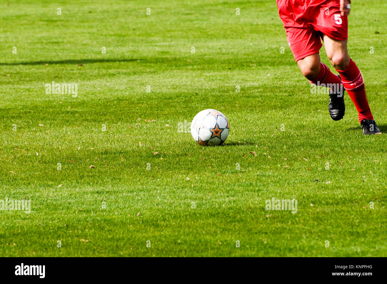 Le gambe di un giocatore di calcio in abito rosso, in azione durante una partita Foto Stock