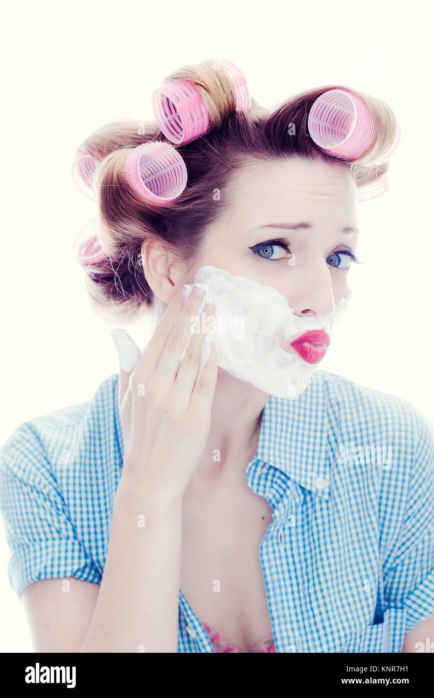 Junge Frau mit Lockenwicklern und Rasierschaum im Gesicht - donna con capelli e rullo di schiuma da barba in faccia Foto Stock