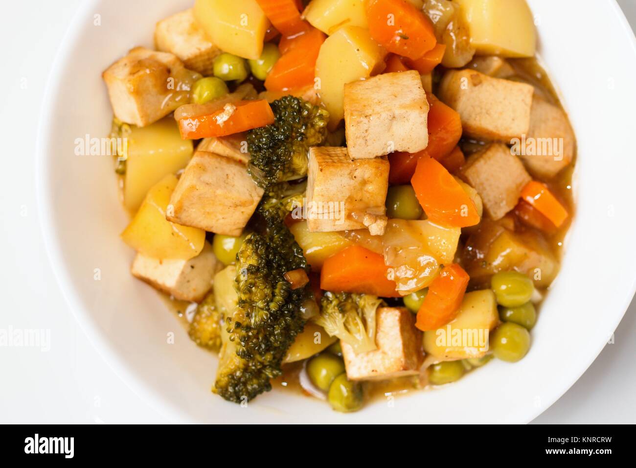 Parte superiore verso il basso vicino sul vaso di verdure cotte con tofu. Concetto di alternativa sana mangiare vegano Foto Stock