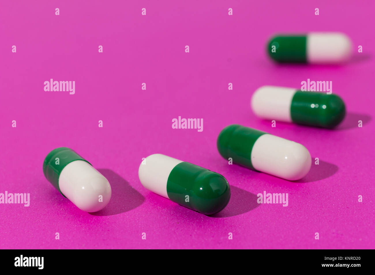 Cumulo di bianco e verde di capsule su sfondo viola. Pillole sono la realizzazione di una linea di percorso o. Concetto di modo, corso. Foto Stock