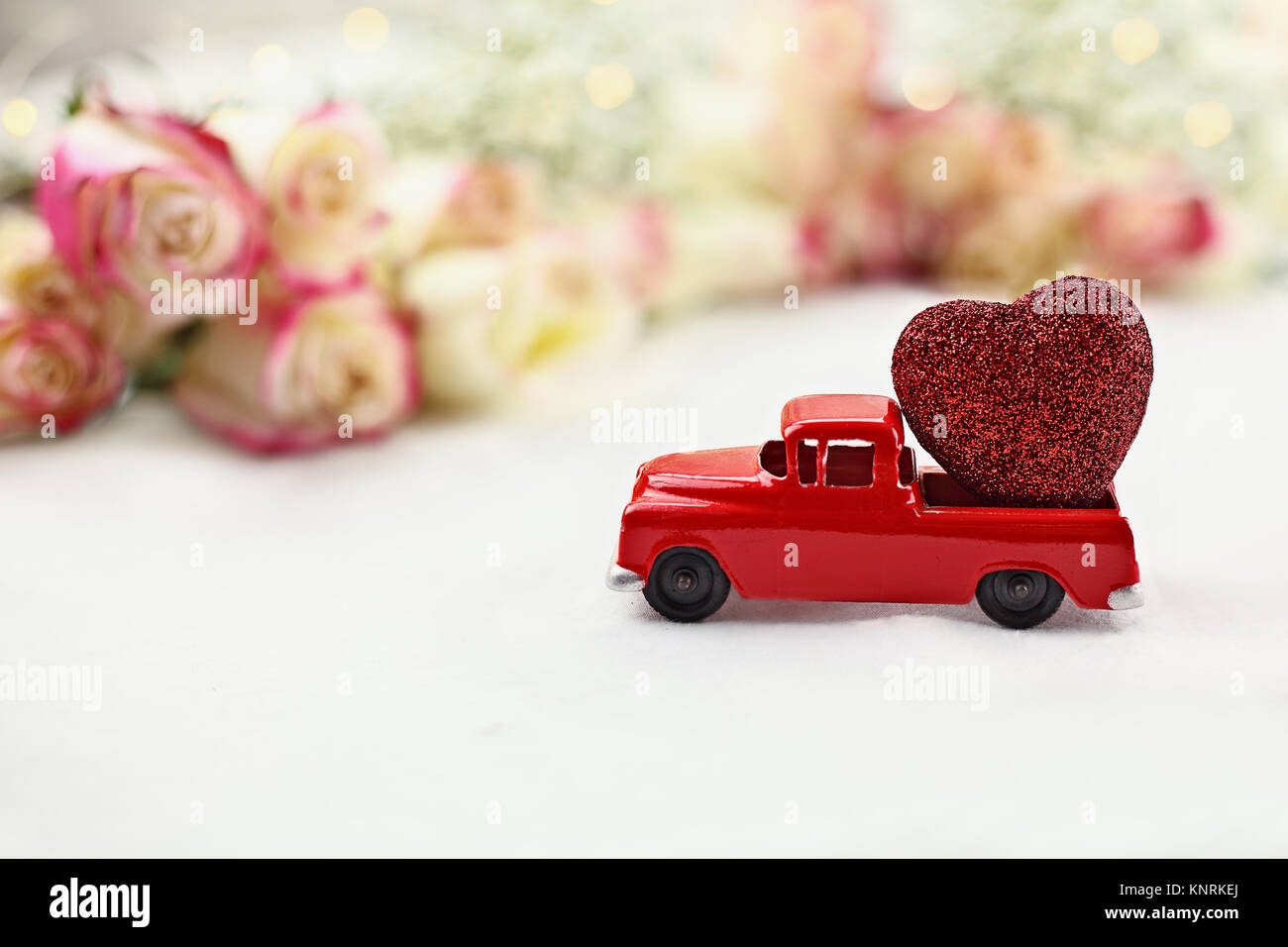 Anni Cinquanta antique vintage red carrello trasporta un glittery cuore rosso passato un rotolo di bella gambo lungo rose. Estrema profondità di campo con il selettivo Foto Stock