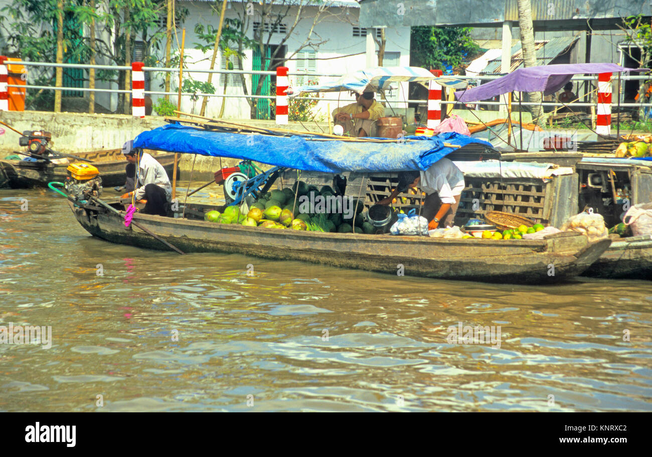 Il Vietnam, Phong Dien, Fiume edifici laterali e il servizio locale di barca con frutta sul fiume Can Tho, Delta del Mekong Foto Stock