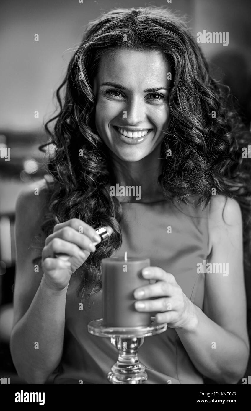 Sorridente giovane casalinga candela di illuminazione in Natale decorato cucina Foto Stock