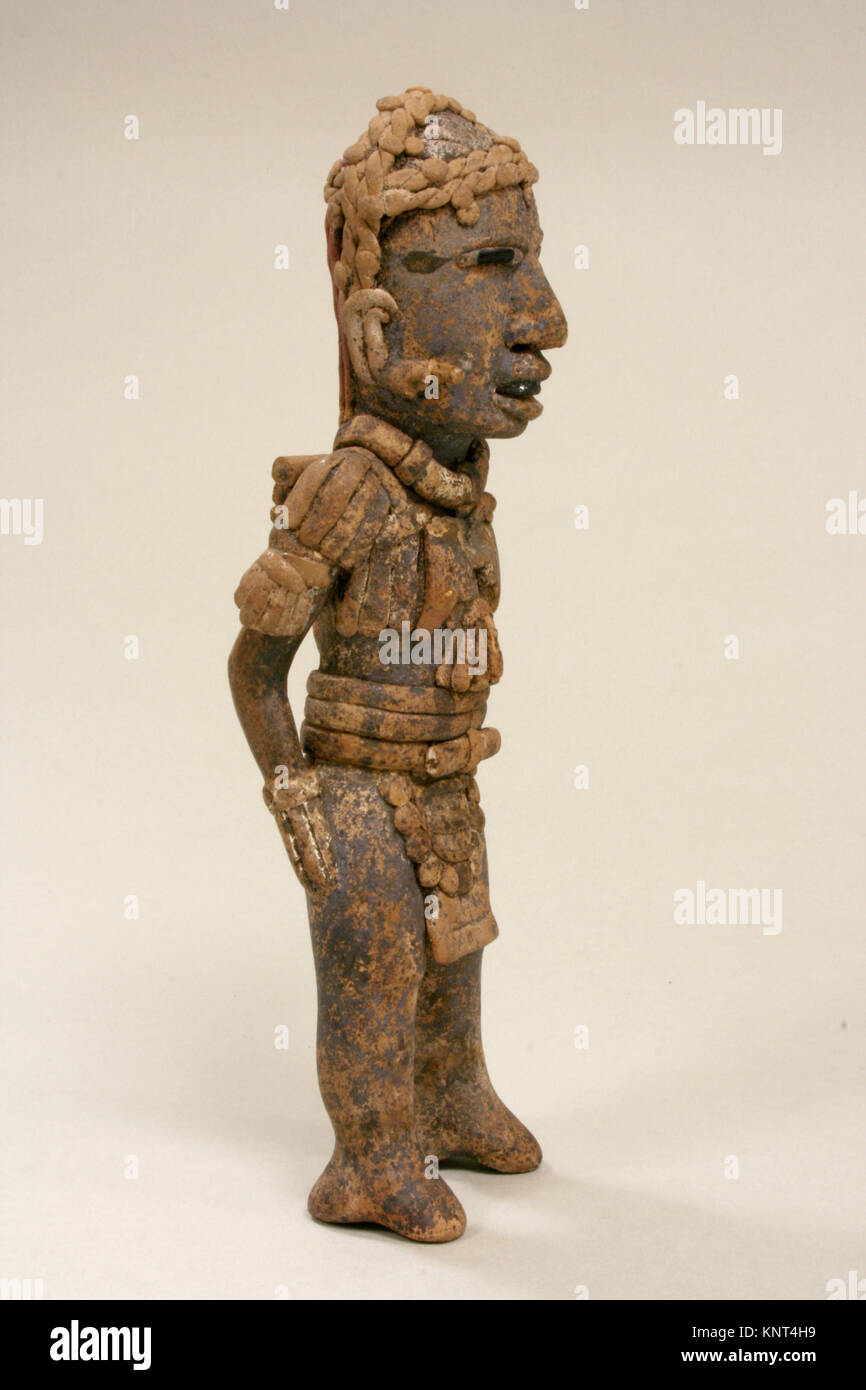 Questa figura in ceramica di Veracruz, datata al periodo classico, ritrae una forma umana in piedi con distintivi capelli o cappello ricciolati, ornamenti toracici simili a barba, ornamenti auricolari sporgenti e un'elaborata cintura o loto. La bocca larga rivela denti anneriti, una caratteristica rara ottenuta con cristalli di ematite. Foto Stock