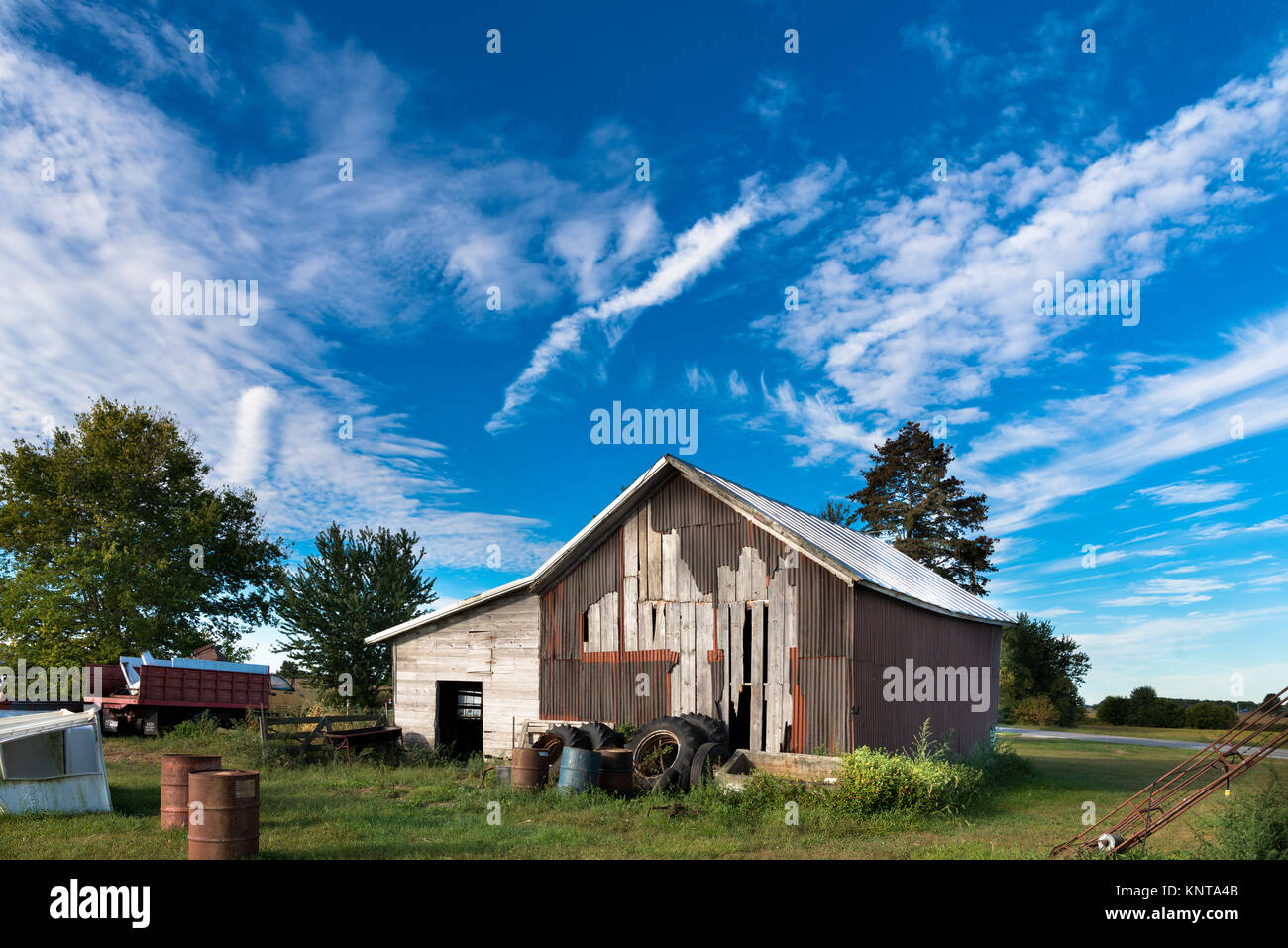 Il vecchio fienile con junk tutto intorno, di fronte a un cielo blu Foto Stock