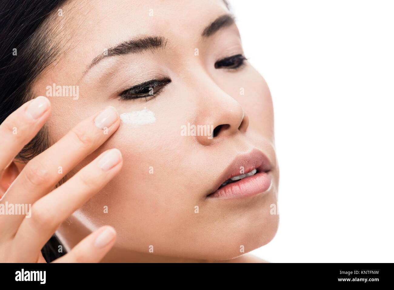 Giovane donna applicando anti-rughe occhio idratante Foto Stock