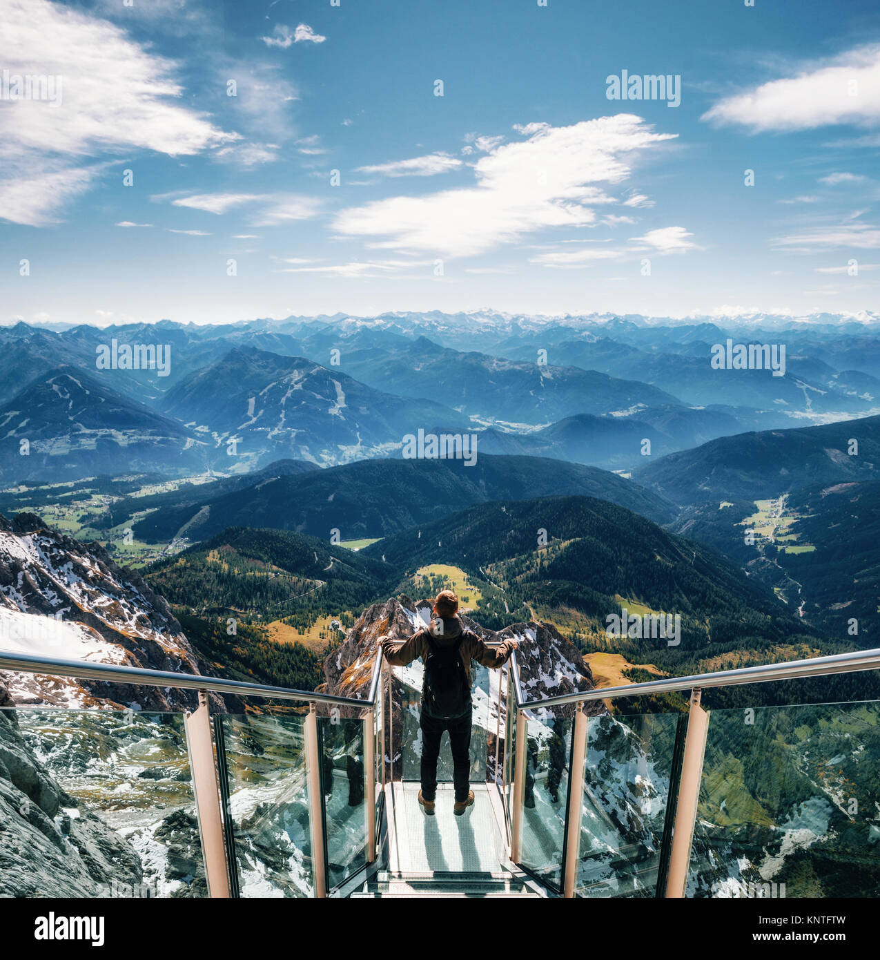 Giovane uomo con zaino sorge sulla piattaforma di osservazione di skywalk ponte di corde monti Dachstein e gode del paesaggio in Austria Foto Stock